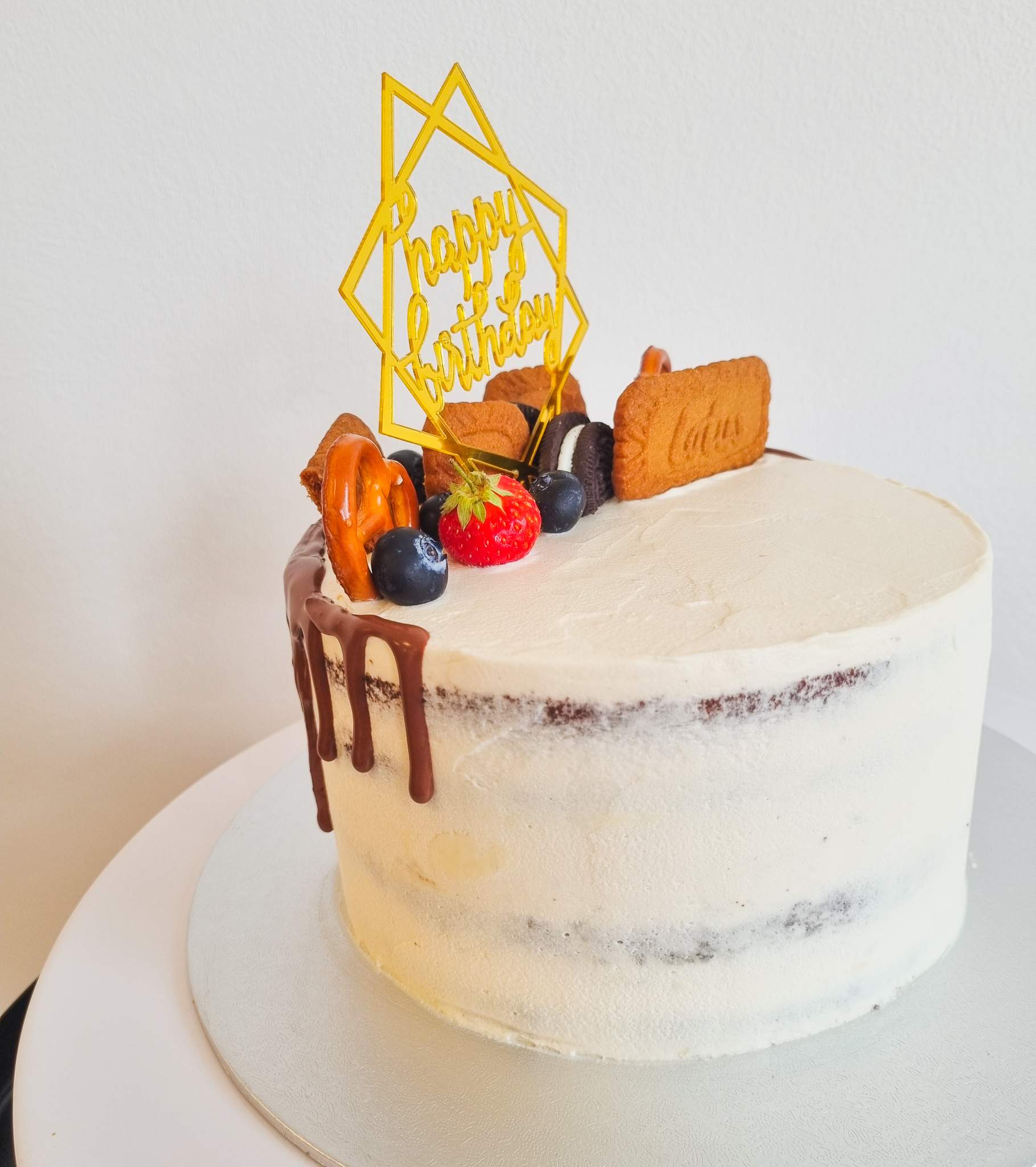 Eine vegane Geburtstagstorte, dekoriert mit Keksen und Früchten